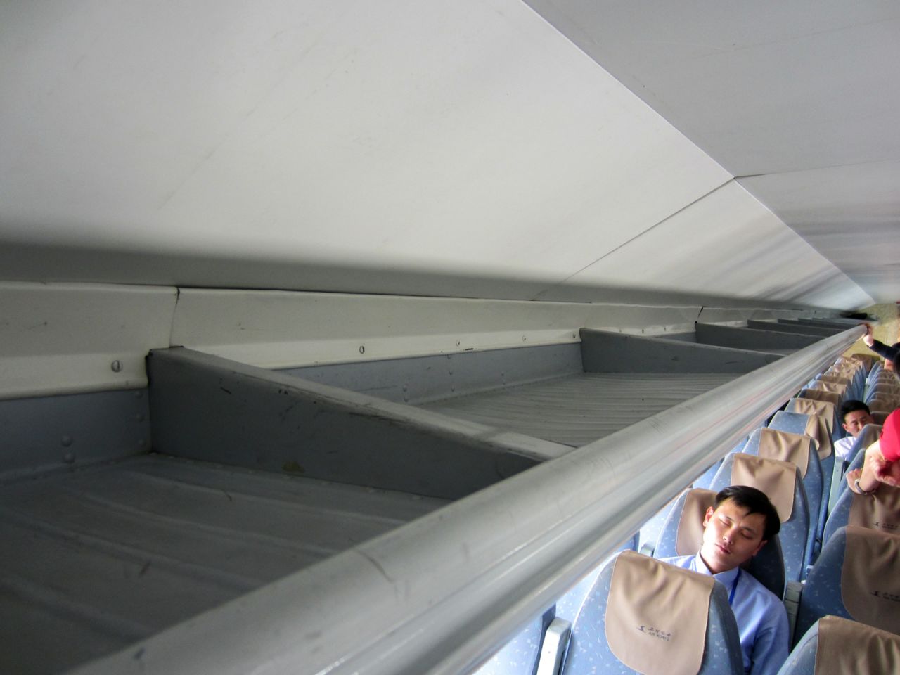 Despite its loud engines, some passengers were able to catch some sleep during the flight. Note the basic design of the plane's overhead storage bins. 