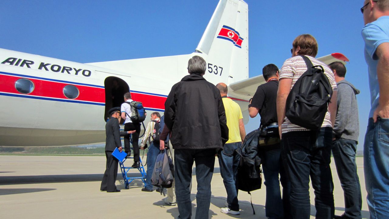 A tour group of about 75 aviation enthusiasts lines up to board a rare Air Koryo airliner.