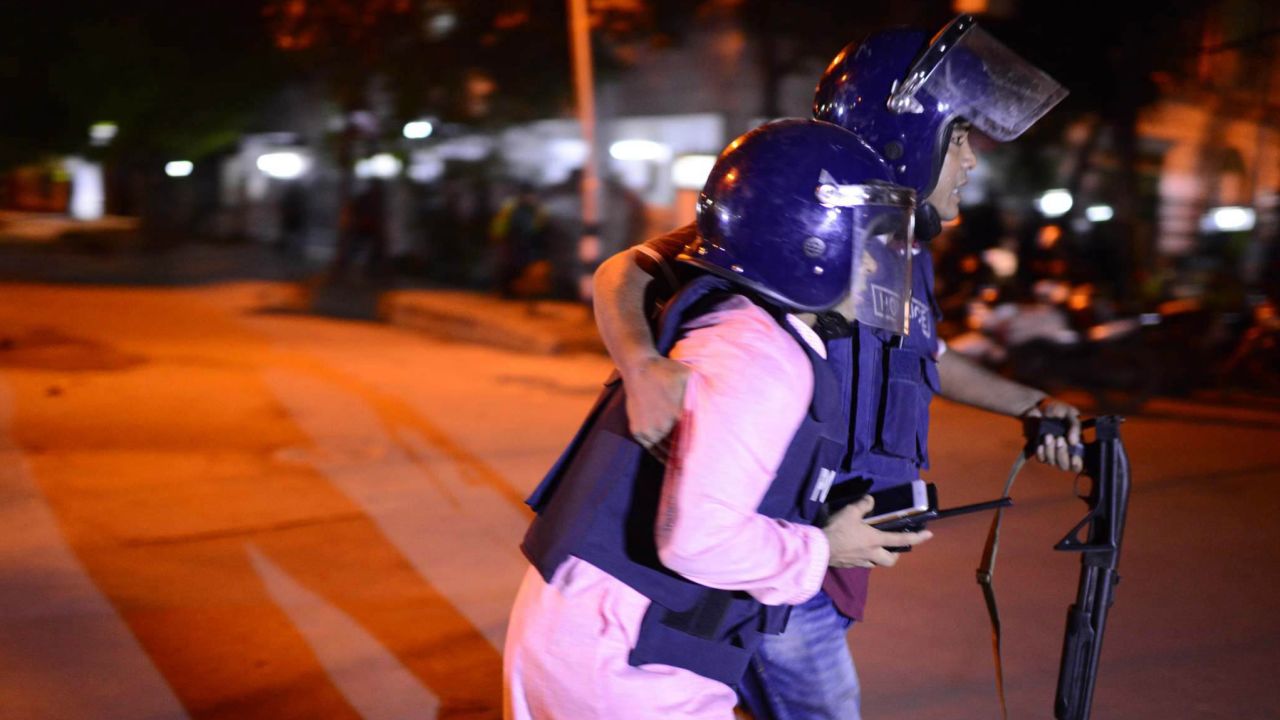 Bangladeshi police take cover after responding to the attack.