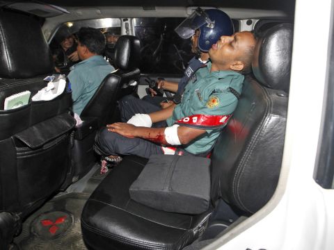 An injured police officer sits in a car. The attackers threw explosives at police as they exchanged gunfire, a source at the scene said.