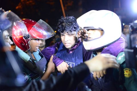 An injured police officer is led away after the cafe attack in the early hours of July 2 in Dhaka. 