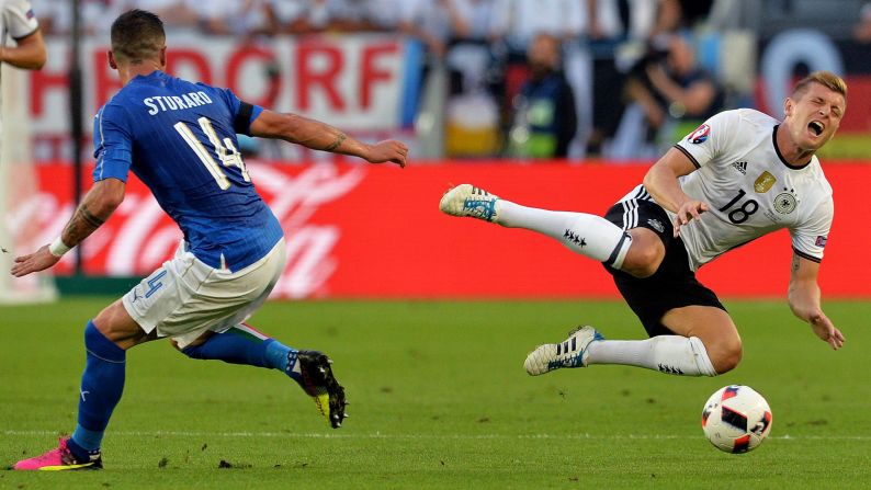 Italy midfielder Stefano Sturaro looks on as Germany midfielder Toni Kroos goes flying.
