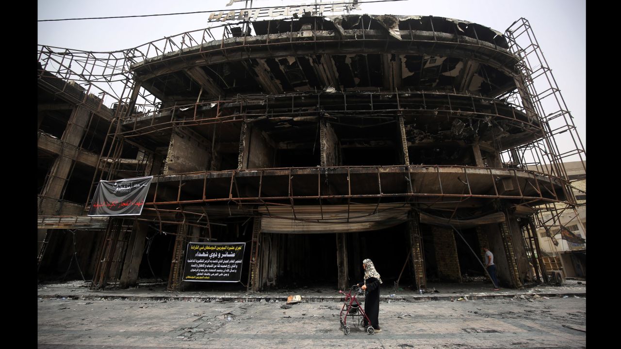 A woman walks by a building that was damaged in the Karrada blast.