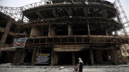 An Iraqi woman walks a building that was damaged during the by a suicide-bombing.