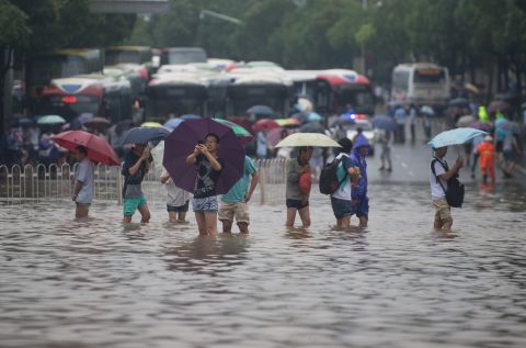 People carrying umbrellas cross a flooded street in Wuhan, July 2. 