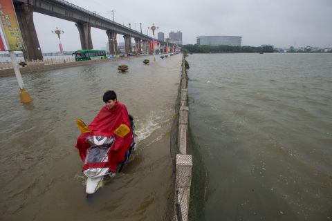 A man rides a scooter across a flooded bridge in Wuhan, July 2.<br />