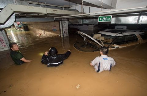 Residents try to remove a car from a flooded parking garage in Wuhan, July 2. <br />