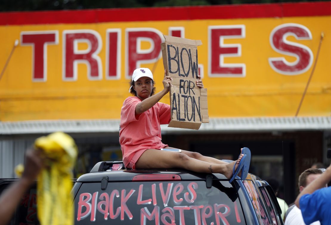 A woman holds up a sign encouraging motorists to honk outside the Triple S convenience store during a rally after Alton Sterling was shot and killed Tuesday.
