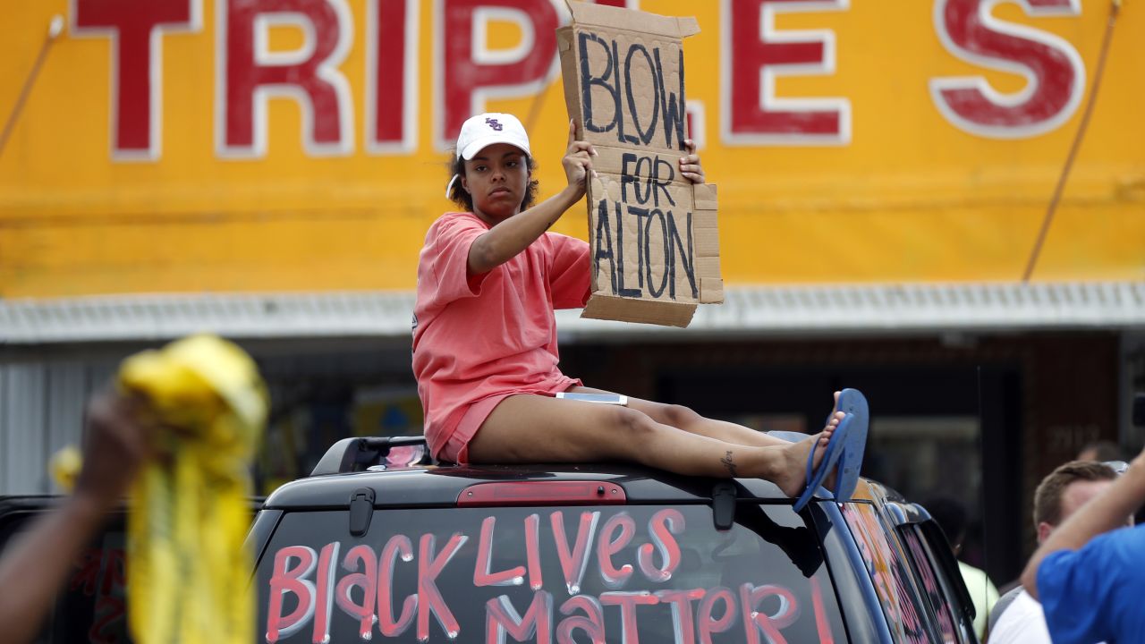 A woman holds up a sign encouraging motorists to honk outside the Triple S convenience store during a rally after Alton Sterling was shot and killed Tuesday.