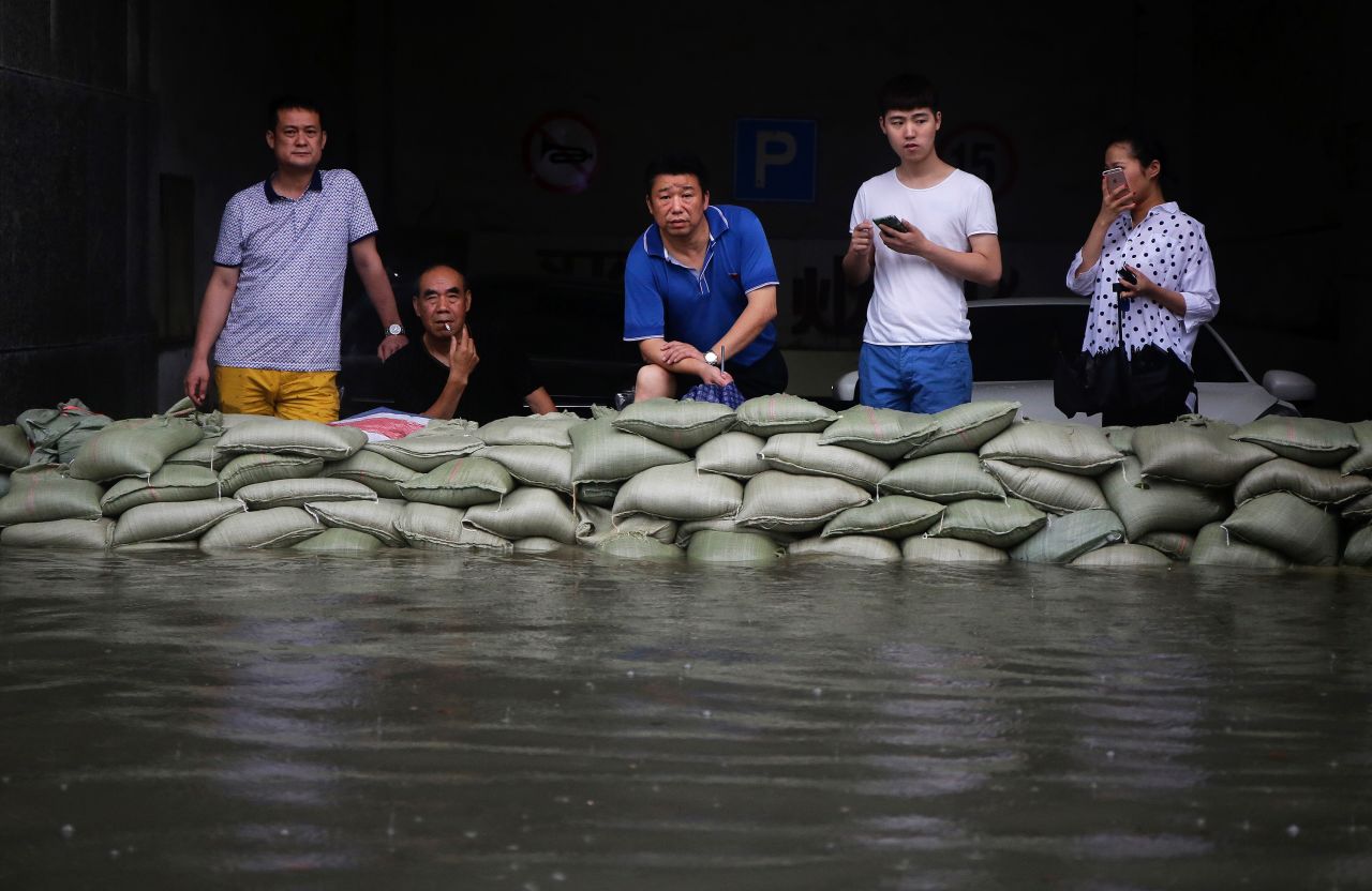 Residents stand behind sandbags on a flooded street in Wuhan, Hubei province, July 6. More than 10 million people in the province have been affected -- a sixth of the population. 
