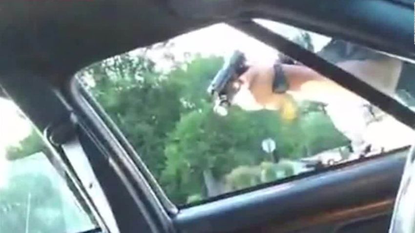 A police officer points a gun through the window of Philando Castile's car window.
