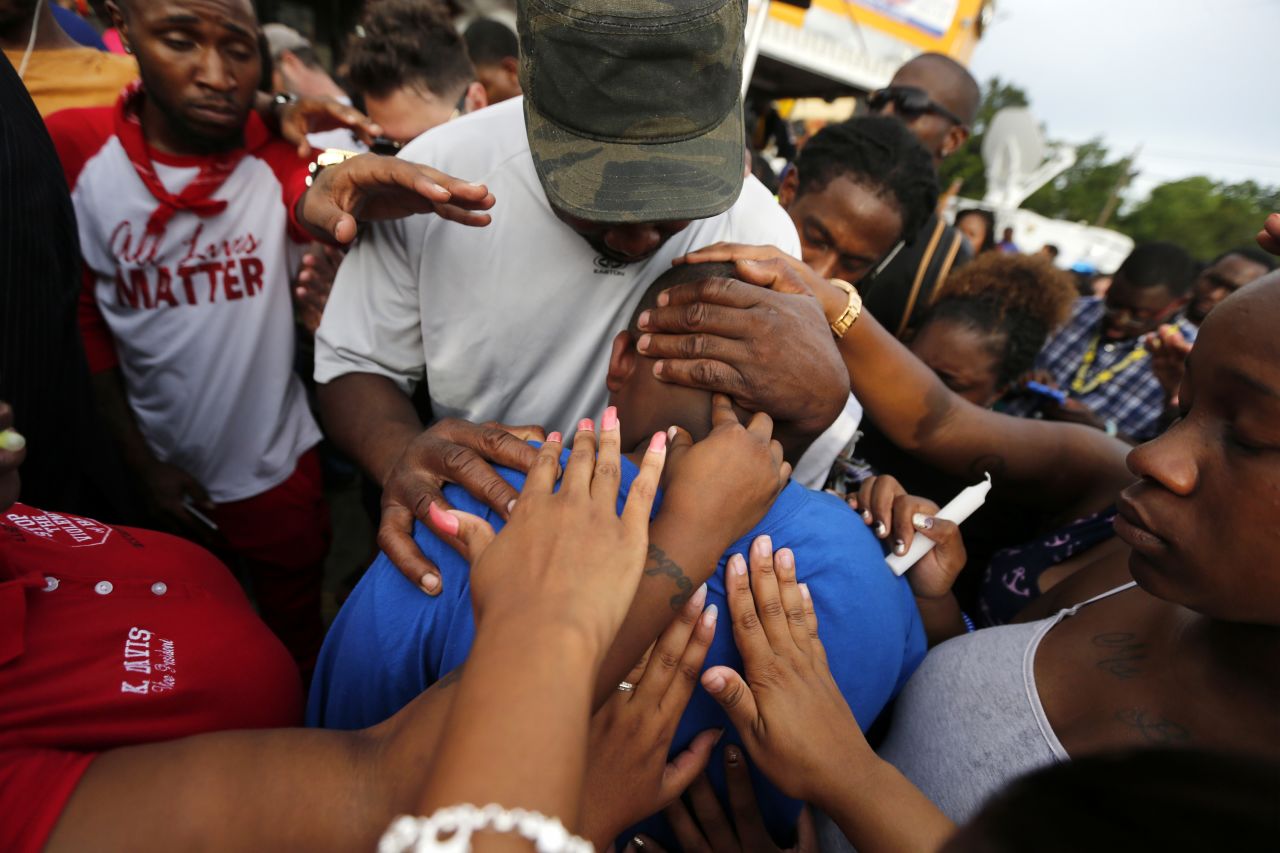 One of Sterling's children, Cameron, is comforted by a crowd outside the convenience store on July 6.