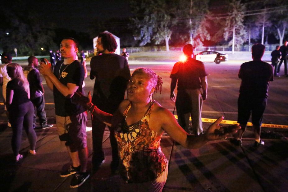 A woman joins others gathered at the scene of a police-involved shooting in Falcon Heights, Minnesota, on July 6. Philando Castile, 32, was fatally shot by police during a traffic stop. His fiancee, Diamond Reynolds, live-streamed the aftermath on Facebook. The shooting is being investigated.