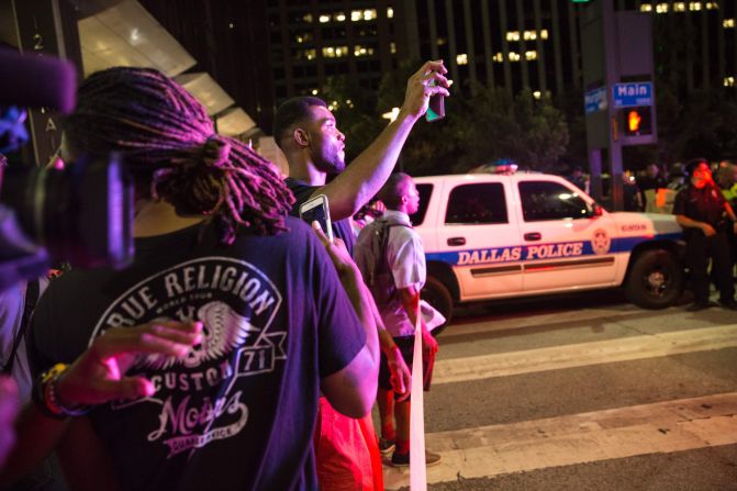 Onlookers stand near police barricades after the shootings. 