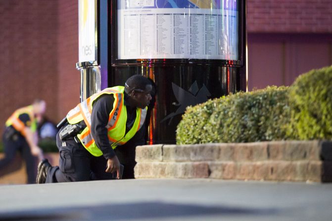 Two officers crouch behind barriers.