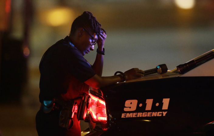 A Dallas police officer takes a moment as she guards an intersection in the early morning hours.