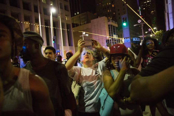 Protesters gather as police officers arrest someone in the aftermath of the shootings.