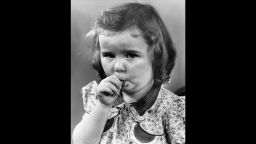 FILE PHOTO: Studio headshot of a young girl sucking on her thumb. She wears a floral dress.  