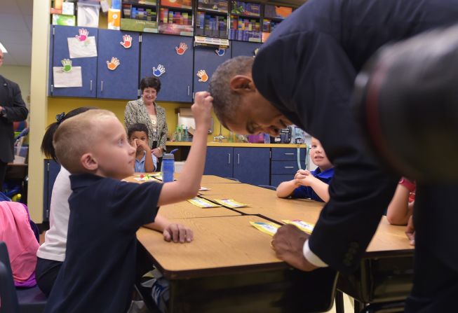 U.S. President Barack Obama leans over for a boy to touch his head during a visit to an elementary school at MacDill Air Force Base in Tampa, Florida, on September 17, 2014.