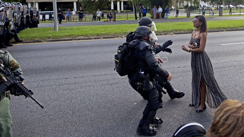 A protester is grabbed by police officers in riot gear after she refused to leave the motor way in front of the the Baton Rouge Police Department Headquarters in Baton Rouge, La., Saturday, July 9, 2016. Several hundred protesters, including members of the New Black Panther party, blocked the roadway causing police to close the road and move the crowd with riot police. Several protesters were arrested.(AP Photo/Max Becherer)