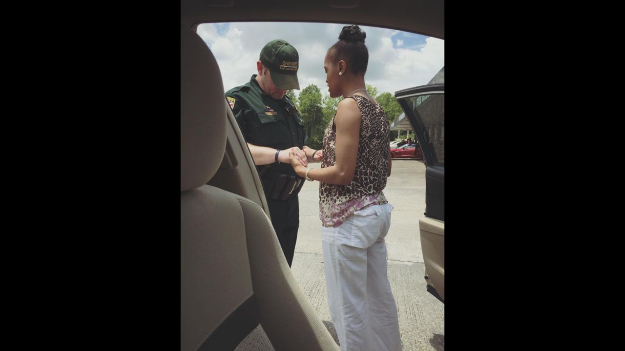 Kim Muyaka -- head bowed, eyes closed, hands tightly entwined with those of an East Baton Rouge police officer -- prays that God would "cover this Police Officer ... and use his hands not to hurt or harm but to protect the citizens." Muyaka posted this now-viral photo to her Facebook page.