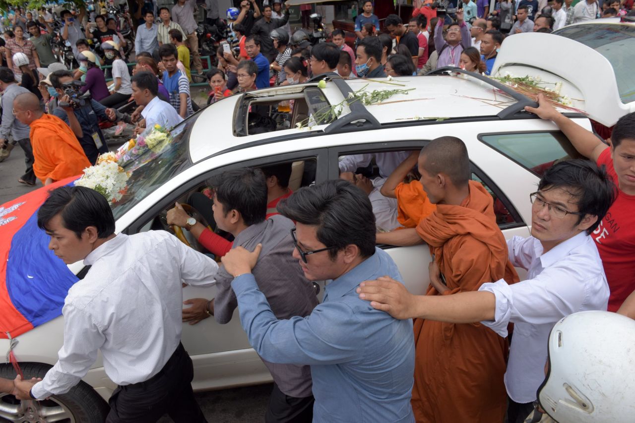 Cambodians walk along a car transporting the body of political commentator and government critic Kem Ley who was shot dead at a convenience store in Phnom Penh on July 10, 2016.
