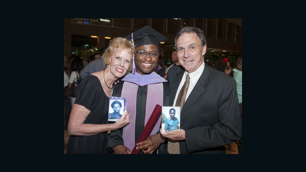 Given Kachepa at his graduation, with foster parents Sandy and Deetz Shepherd, who are holding photos of Kachepa's birth parents.
