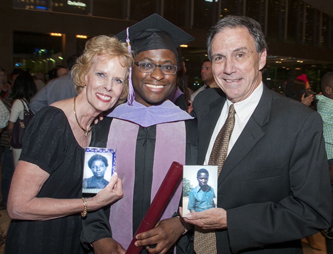 Given Kachepa at his graduation, with foster parents Sandy and Deetz Shepherd, who are holding photos of Kachepa's birth parents.