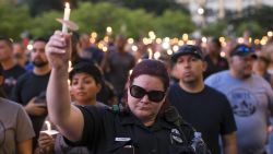 People and police officers attend a candlelight vigil for five police officers killed during anti-police brutality protests, in Dallas, Texas, on July 11, 2016.  Five officers were killed and seven others were wounded when a gunman opened fire on a  protest against recent police-involved shootings. 