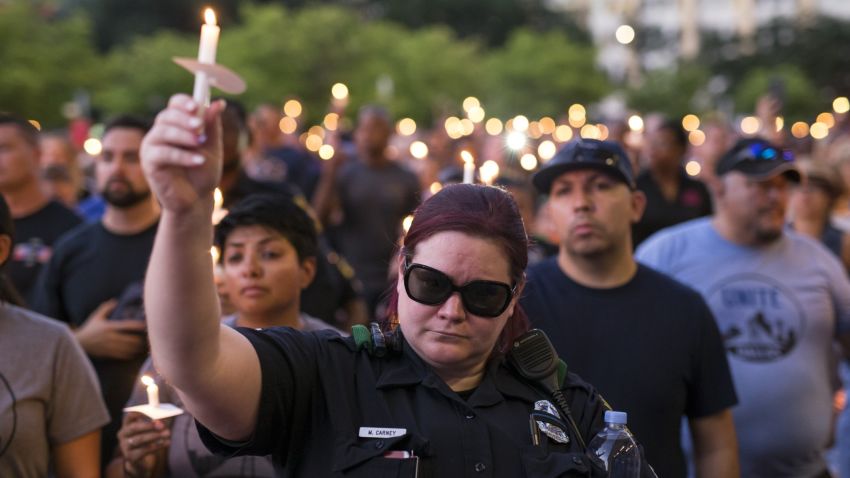 People and police officers attend a candlelight vigil for five police officers killed during anti-police brutality protests, in Dallas, Texas, on July 11, 2016.  Five officers were killed and seven others were wounded when a gunman opened fire on a  protest against recent police-involved shootings. 