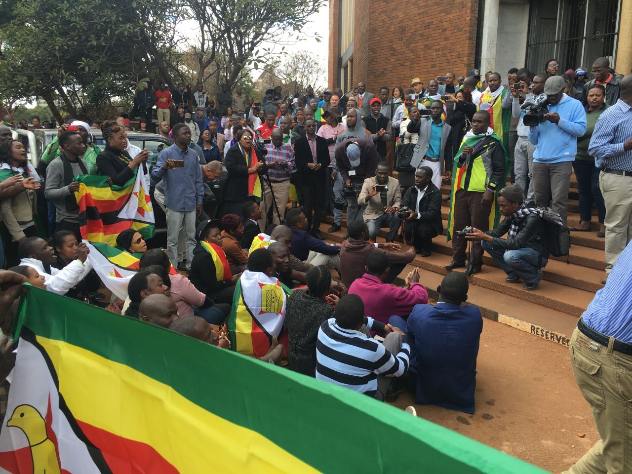 People gather draped in flags as Zimbabwean pastor Evan Mawarire appeared in court. 