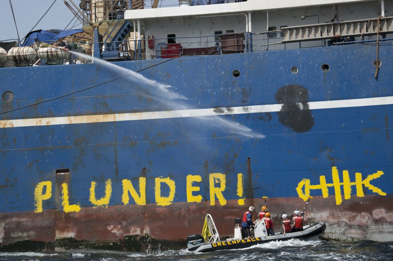 Activists from the Greenpeace ship Arctic Sunrise paint "Pillage and Plunder" on side of pirate Russian pelagic fishing trawler Oleg Naydenov off the coast of Senegal.