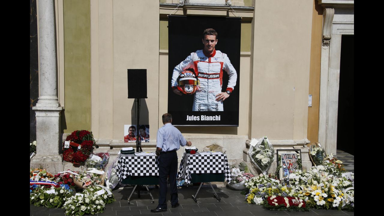 A man pays his respects below a poster showing Bianchi, after the driver's funeral ceremony at the Cathedrale Sainte Reparate in Nice on July 21, 2015, in southeastern France.