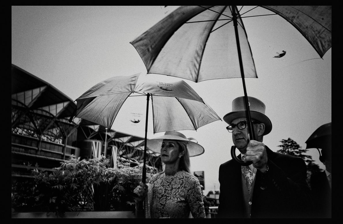 Though racegoers are dressed to the nines, in Britain there are no guarantees it won't rain. Pictured, racegoers coupling sartorial elegance with England's obligatory umbrellas.