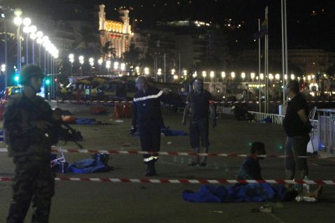 Soldiers, police officers and firefighters walk among bodies covered with blue sheets on the seafront Promenade des Anglais.