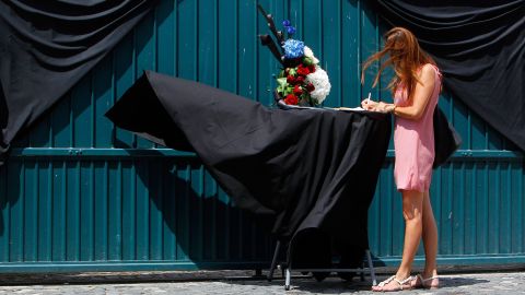 A woman signs a condolence book in front of the French Embassy in Bucharest, Romania.