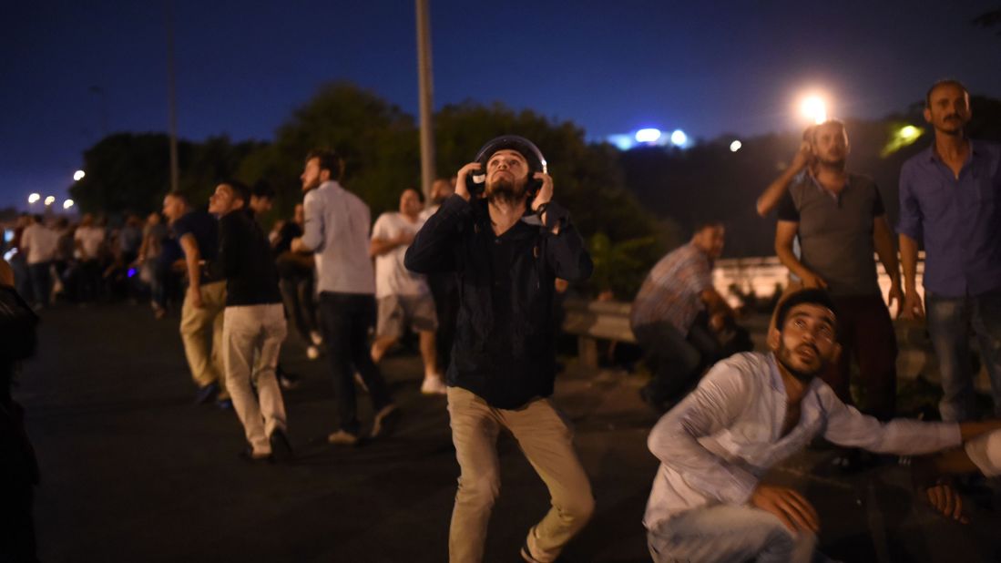 People take cover near the Bosphorus Bridge as military airplanes fly overhead.