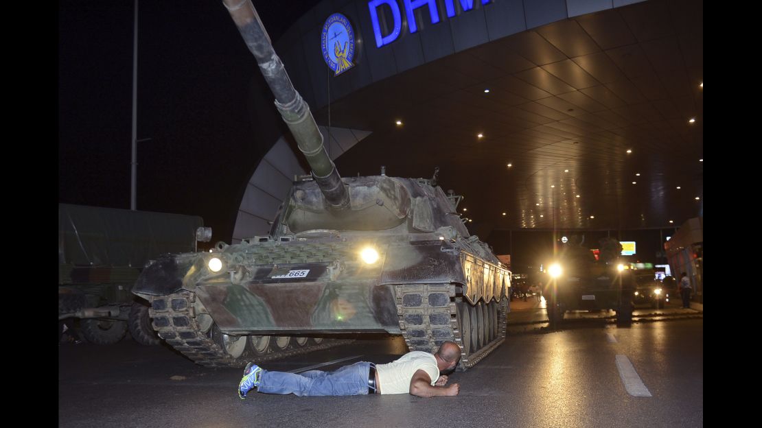 A man lays in front of a tank at the entrance to Istanbul Ataturk Airport.