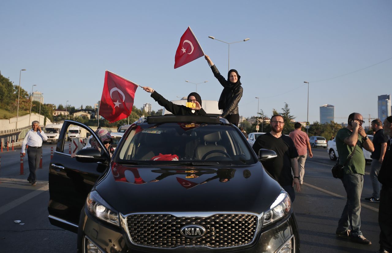 Turkish people wave national flags from a car in Istanbul.