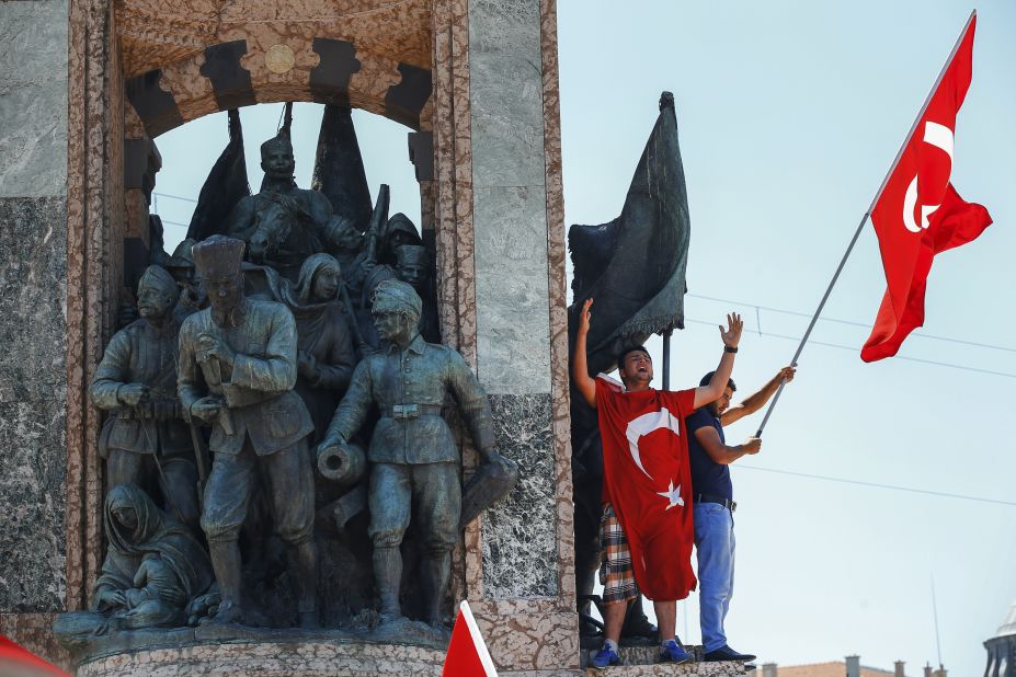 People protesting against the coup wave a Turkish flag on top of a monument in Istanbul's Taksim Square.