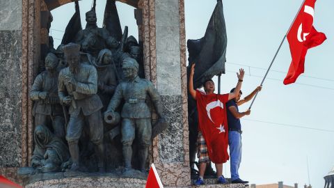 People protesting against the coup wave a Turkish flag on top of a monument in Istanbul's Taksim Square.