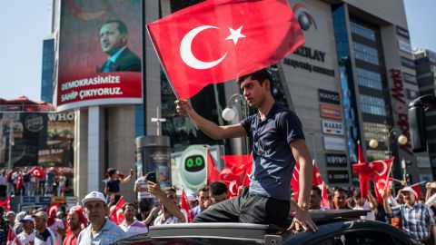A man waves a Turkish flag from the roof of a car during a march around Ankara's Kizilay Square.