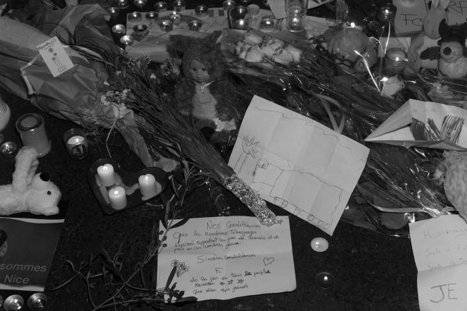 People left candles and messages at a memorial site. On one of the pieces of paper, a child drew a truck.