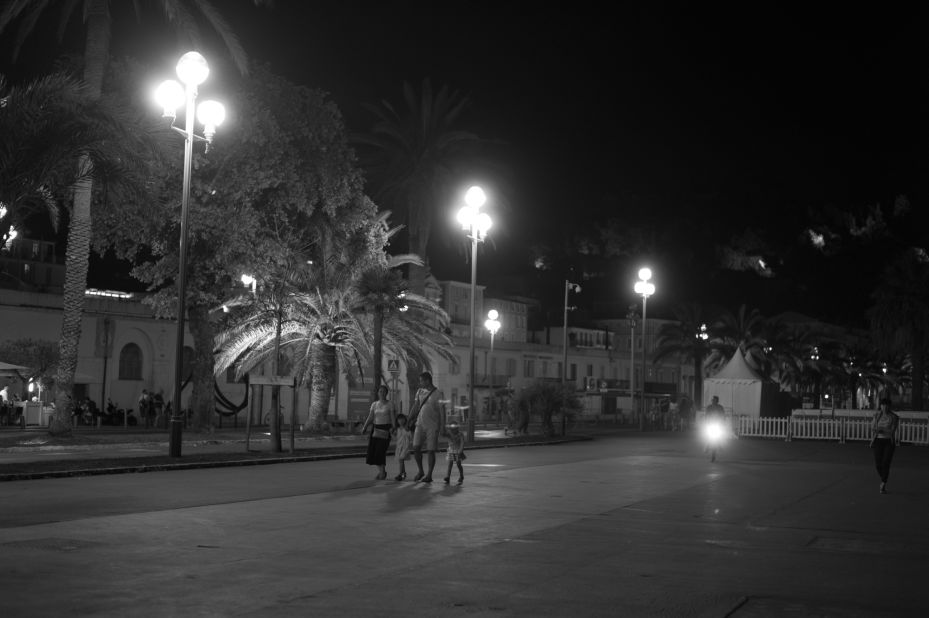 People hold hands as they walk on the Promenade des Anglais.