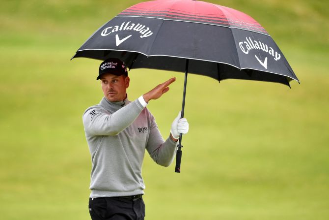 Stenson takes shelter from the intermittent showers on the third day.