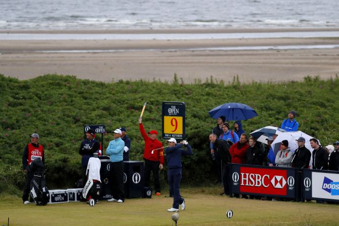 The umbrellas are up and the sea breeze is picking up as Charl Schwartzel of South Africa hits his tee shot on the ninth hole at Royal Troon.