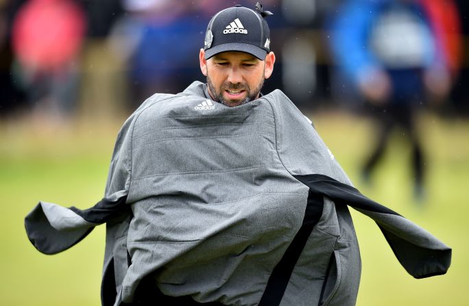 Spain's Sergio Garcia protects himself from the elements during his third round of 73 to go into the clubhouse on 211 -- two under.