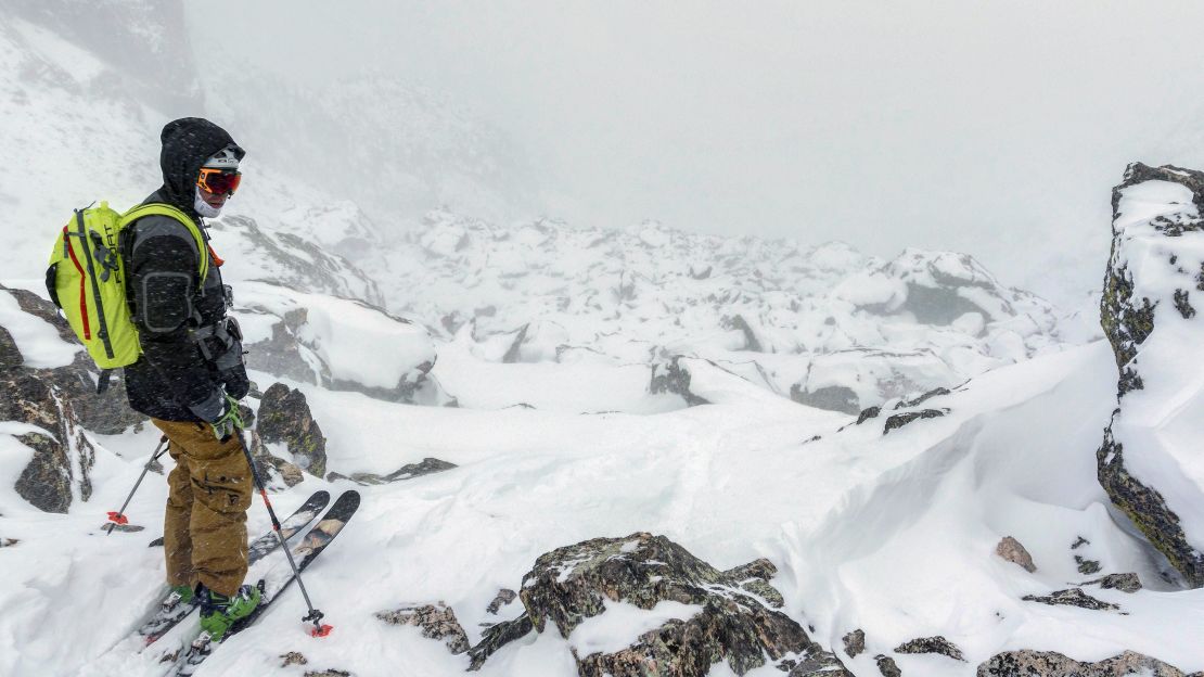 Austin Porzak pauses on a descent. Deep powder and jagged rocks present hurdles.