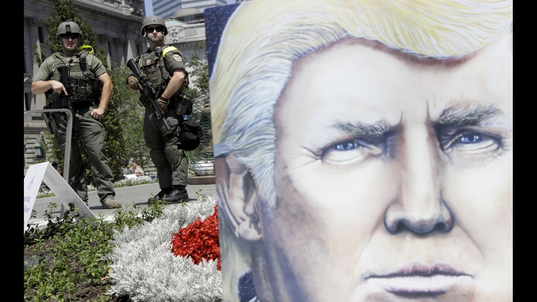 Law enforcement officers stand watch Tuesday in Public Square, near a large poster of Republican presidential candidate Donald Trump.