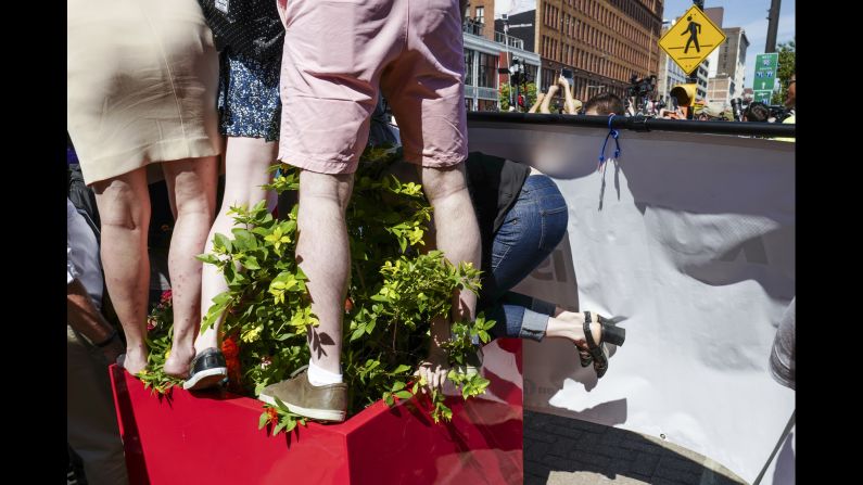 A woman climbs onto a plant stand outside the entrance to Quicken Loans Arena, the scene of the convention. The arena is home to LeBron James and the NBA champion Cleveland Cavaliers.